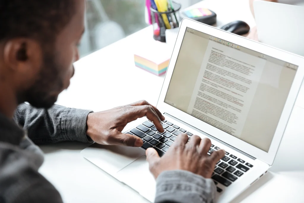 A serious young man typing on a laptop, focused on creating a professional resume. Learn how to write a resume with Advanced Employment Services.