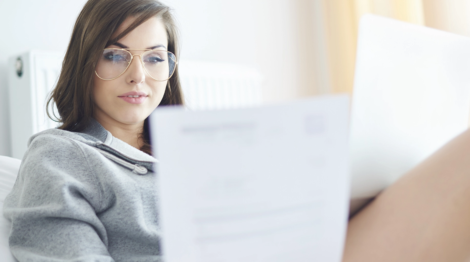 A young woman working from home, reviewing her resume on a laptop. Discover tips on how to write a resume with Advanced Employment Services.