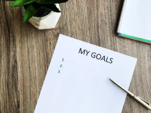 A clipboard with a 'My Goals' list on a wooden desk, symbolizing the importance of setting goals for career advancement with the help of Advanced Employment Services.