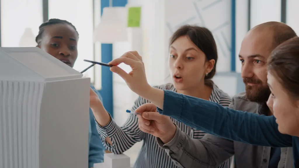 Close-up of workmates analyzing a building model, showcasing teamwork, productivity, and a motivating work culture facilitated by Advanced Employment Services.