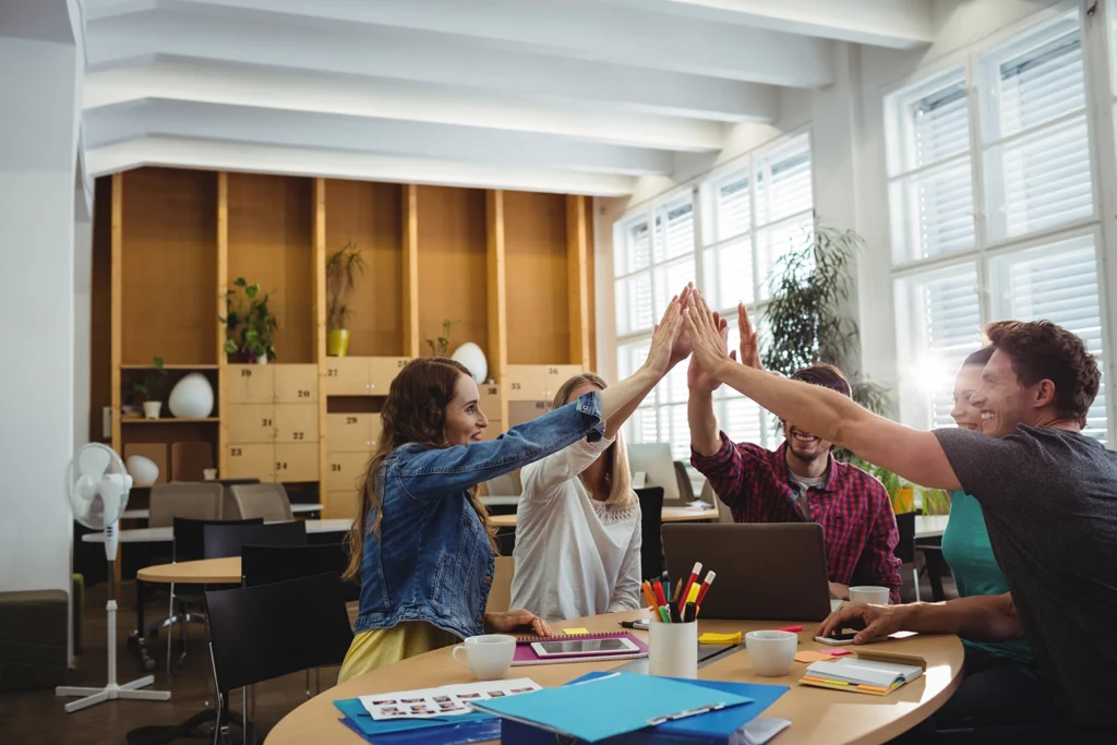 A creative business team uniting their hands in a group gesture, symbolizing collaboration and engagement within a productive office culture, facilitated by Advanced Employment Services.