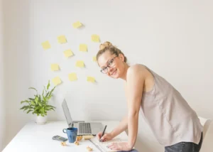 A happy businesswoman writing in her schedule diary, representing the productivity and motivating work culture fostered by Advanced Employment Services.