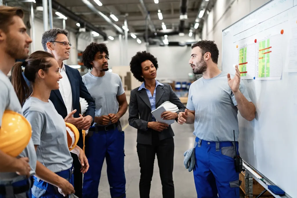 A manual worker presenting a new business strategy to company managers and colleagues, illustrating the importance of effective delegation in the workplace, facilitated by Advanced Employment Services.