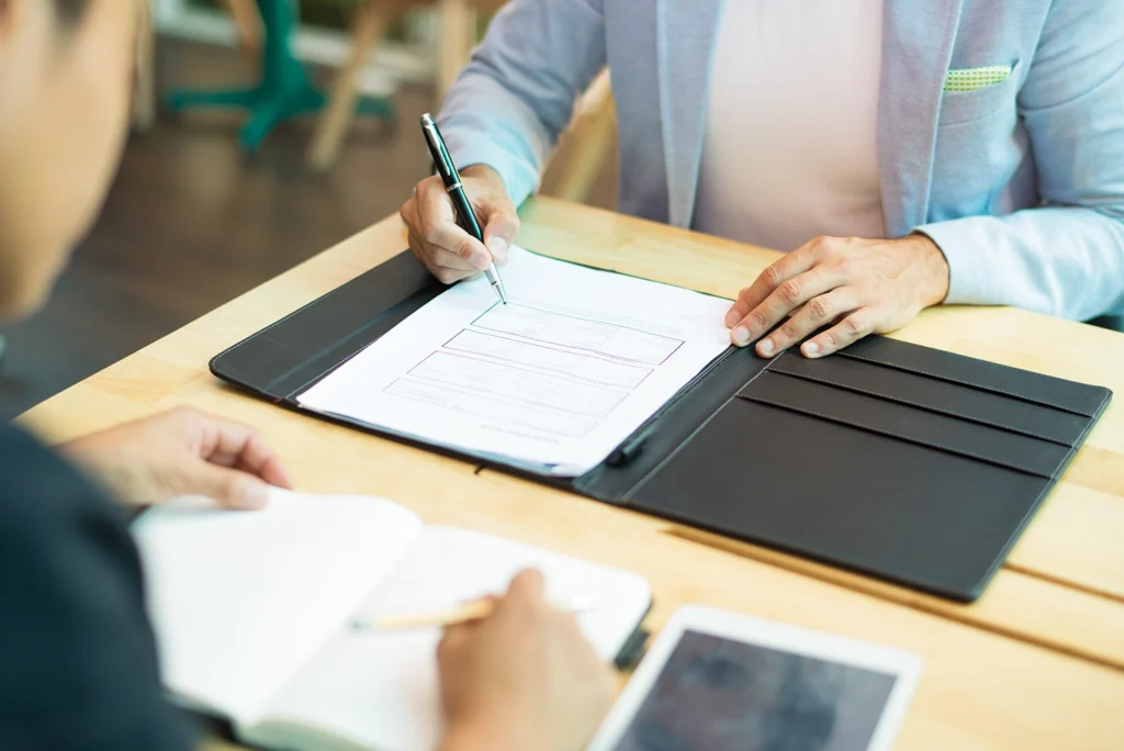 Businessman carefully filling out an employee contract as part of the hiring process, highlighting attention to detail. Advanced Employment Services tips on employee contracts.