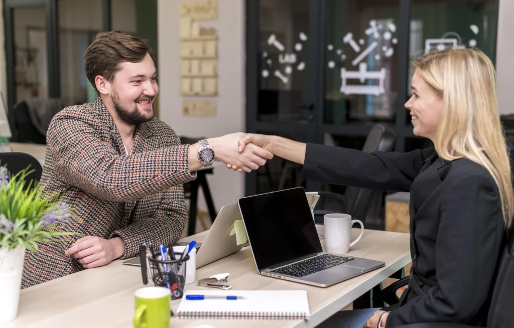 Employer and prospective employee shaking hands after finalizing an employee contract, representing a successful hiring process. Advanced Employment Services expertise in employee contracts.